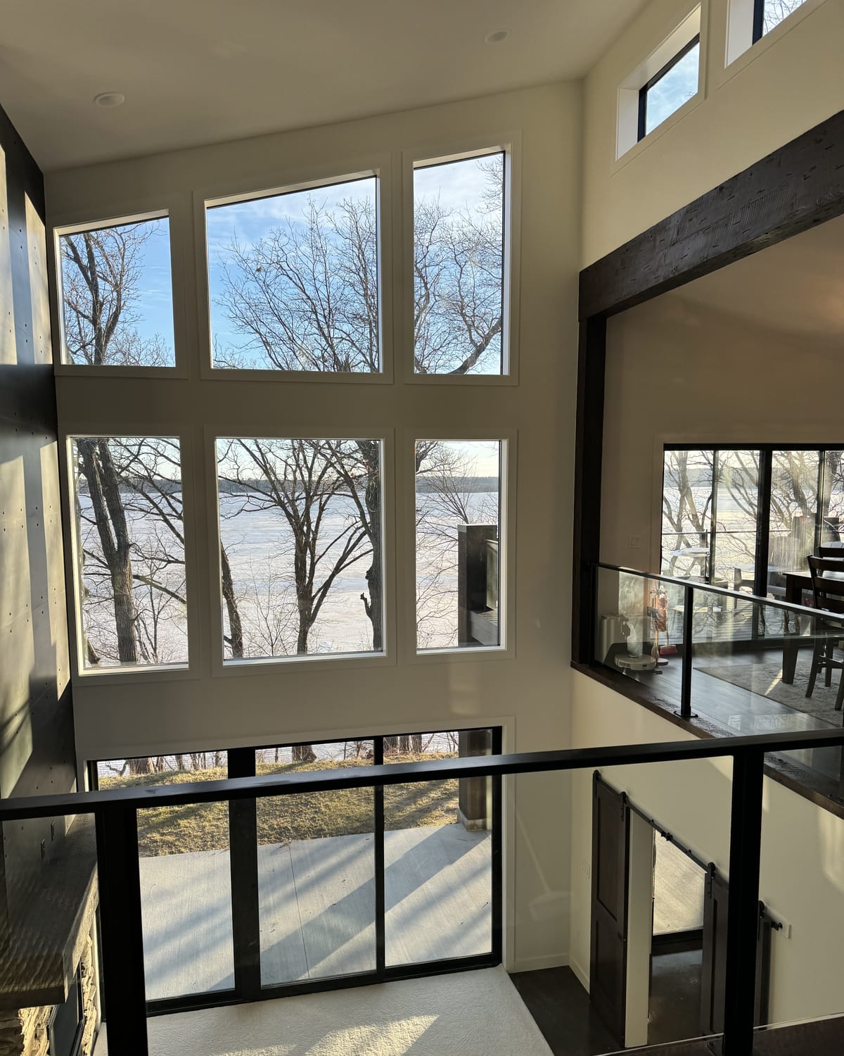 The stair, looking up through the volume past black-framed glass railings.